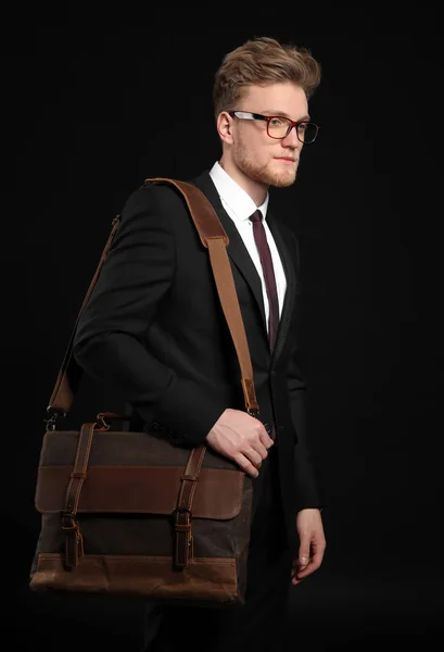 Красивый бизнесмен со стильным портфелем на темном фоне — стоковое фото