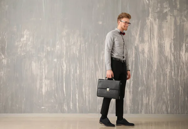 Красивый бизнесмен со стильным портфелем возле серой стены — стоковое фото