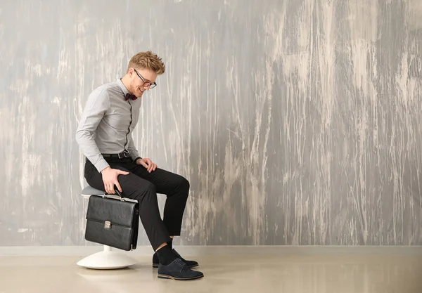 Hombre de negocios guapo con elegante maletín cerca de la pared gris — Foto de Stock