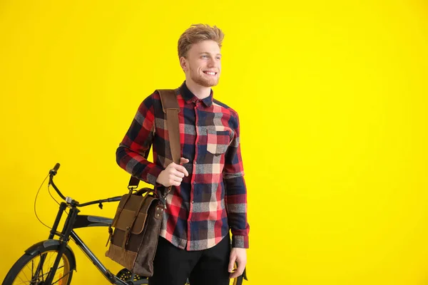 Handsome man with stylish briefcase and bicycle on color background — Stock Photo, Image