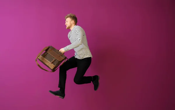 Hombre saltando con un elegante maletín sobre fondo de color —  Fotos de Stock