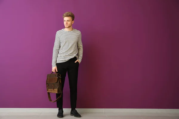 Handsome man with stylish briefcase near color wall