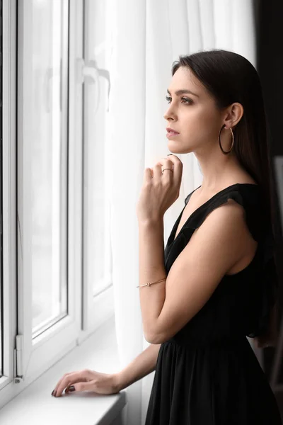 Ung kvinna med vackra smycken nära fönster — Stockfoto
