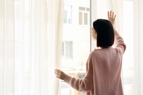 Young woman opening curtains in morning — Stock Photo, Image