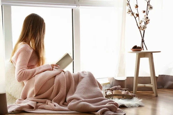 Giovane donna che legge libro vicino alla finestra — Foto Stock