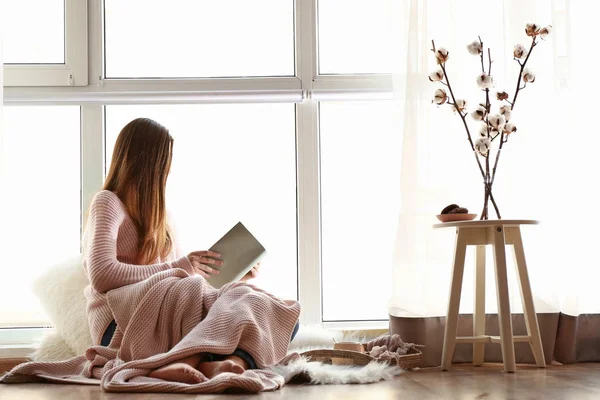 Young woman reading book near window — Stock Photo, Image