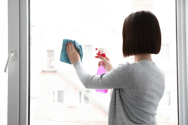 Young woman cleaning window in flat — Stock Photo, Image