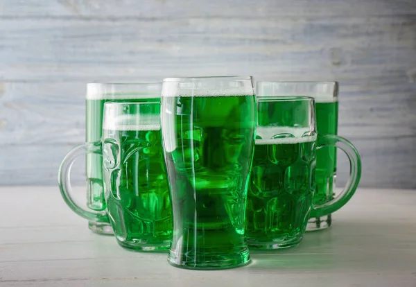 Glassware with green beer for St. Patrick's Day on wooden table — Stock Photo, Image