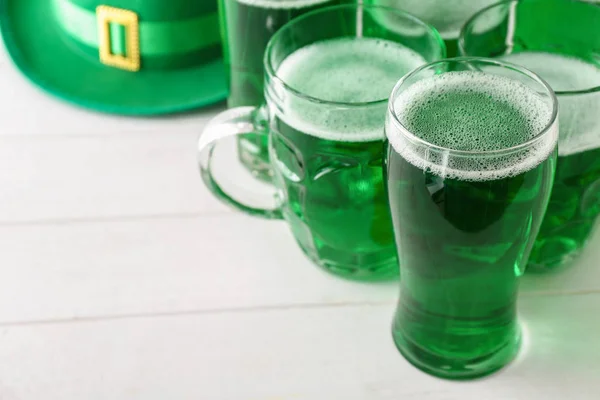 Glassware with green beer for St. Patrick\'s Day on wooden table