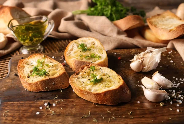 Sliced bread with olive oil, garlic and herbs on wooden table — Stock Photo, Image