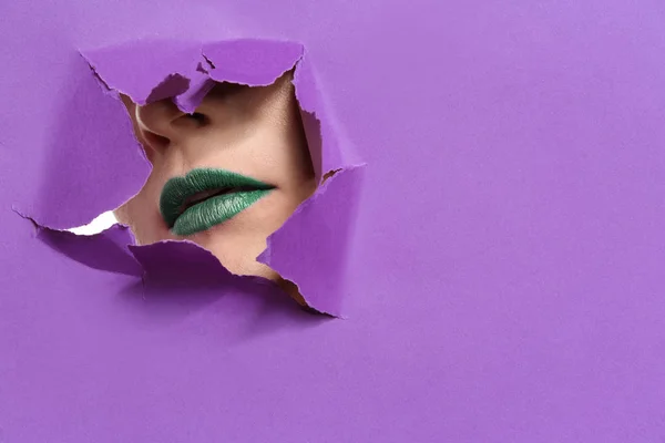 Mulher bonita com maquiagem brilhante visível através de furo em papel colorido — Fotografia de Stock