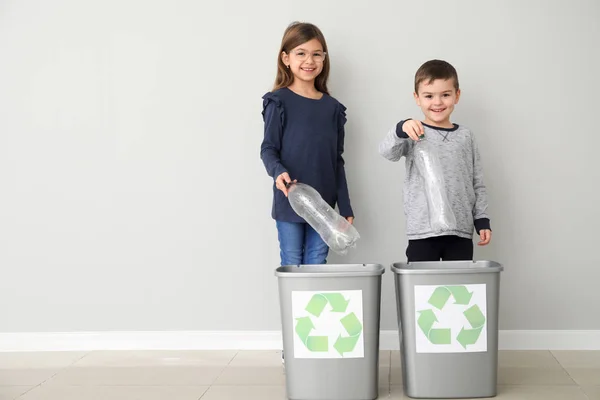 Niños tirando basura en cubos de basura cerca de la pared de luz. Concepto de reciclaje — Foto de Stock
