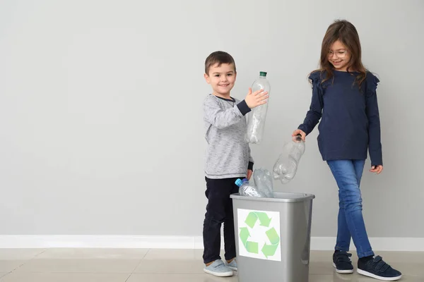Dzieci, wyrzucanie śmieci do kosza w pobliżu ściana światło. Koncepcja recyklingu — Zdjęcie stockowe