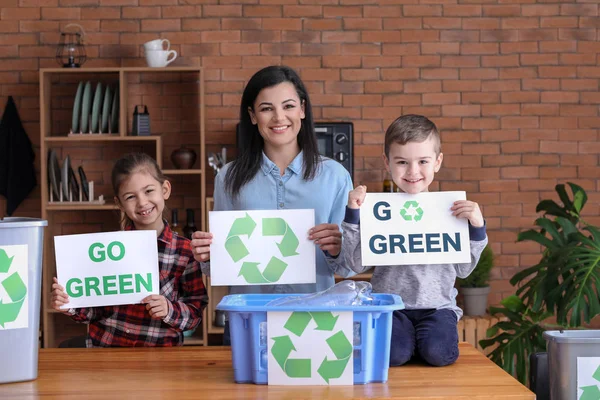 Family holding paper sheets with text GO GREEN and recycling symbol at home