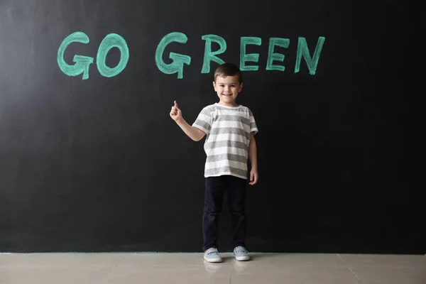 Malý chlapec tmavé zdi s textem Go Green — Stock fotografie