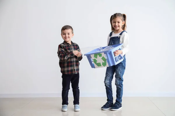 Niños pequeños con canasta para basura cerca de la pared blanca. Concepto de reciclaje — Foto de Stock