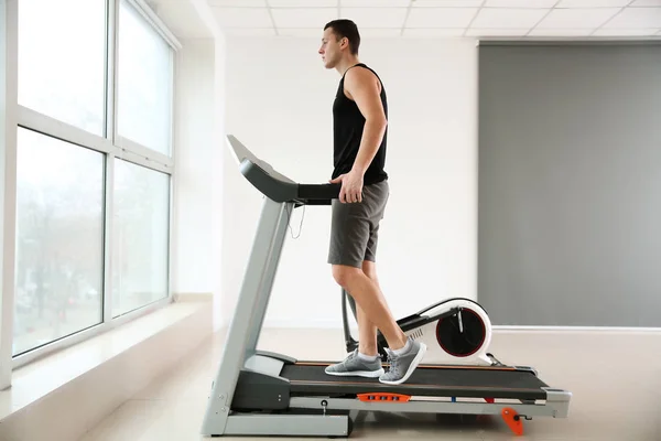 Sportlicher junger Mann auf Laufband im Fitnessstudio — Stockfoto