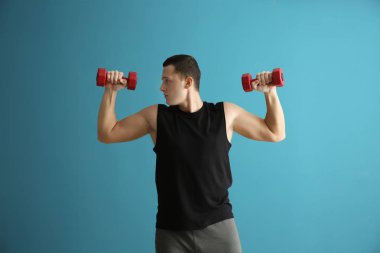 Renk arka plan karşı dumbbells ile eğitim sportif genç adam