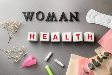 Cubes composed words WOMAN and HEALTH on grey table clipart