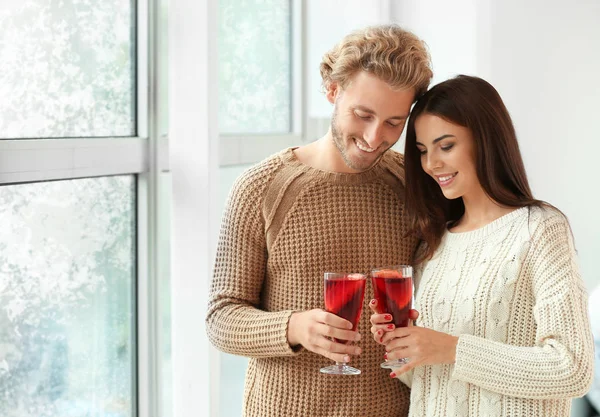 Casal com delicioso vinho quente perto da janela em casa — Fotografia de Stock