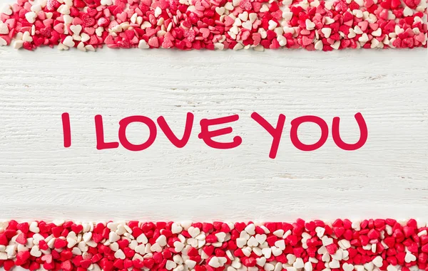 Pequeños corazones de color con texto TE AMO sobre fondo de madera blanca. Celebración de San Valentín — Foto de Stock