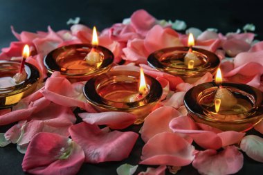 Divaly kutlama koyu arka plan üzerinde çiçek yaprakları ile yanan mumlar