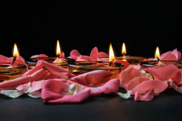 Burning candles with flower petals for celebration of Divaly on dark background — Stock Photo, Image