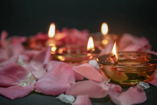 Burning candle with flower petals for celebration of Divaly on dark background, closeup — Stock Photo, Image