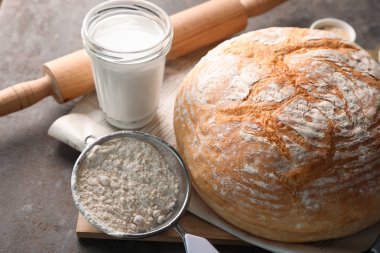 Gri arka plan üzerinde hamur için malzemeler ile lezzetli ekmek