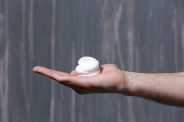 Gri arka plan üzerinde köpük tıraş ile erkek el