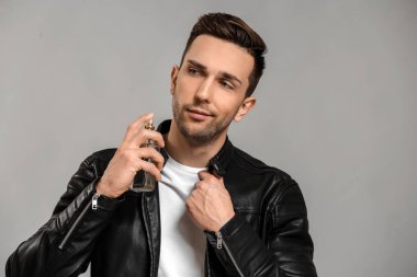 Yakışıklı adam gri arka plan üzerinde parfüm şişe
