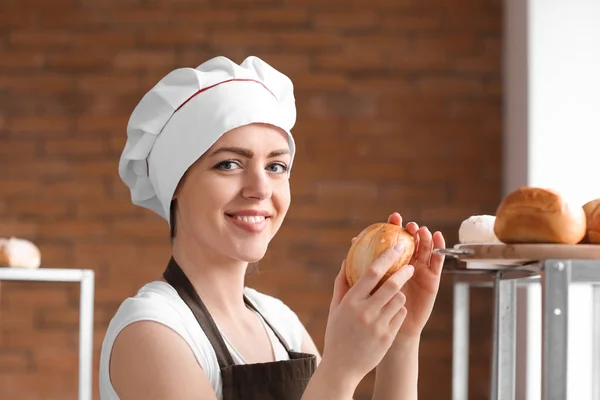 Vrouwelijke chef-kok met versgebakken broodjes in keuken — Stockfoto