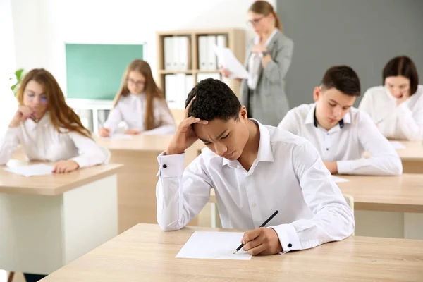 Alunos passando no teste escolar em sala de aula — Fotografia de Stock