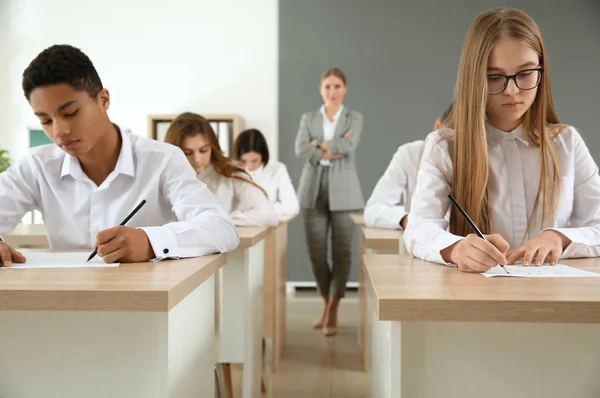 Pupils passing school test in classroom