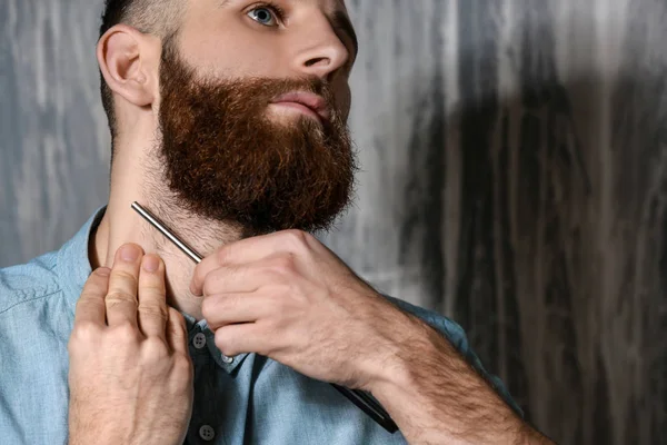 Bärtiger Mann rasiert sich auf grauem Hintergrund — Stockfoto