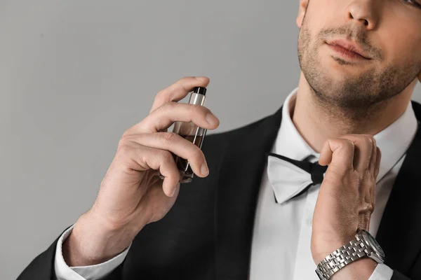 Handsome man with bottle of perfume on grey background, closeup — Stock Photo, Image