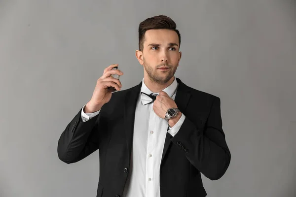 Hombre guapo con botella de perfume sobre fondo gris — Foto de Stock