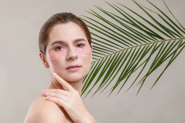 Woman with under-eye patches on grey background