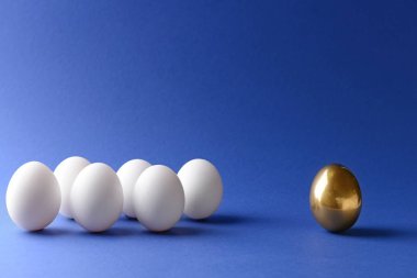 Golden egg among white ones on color background. Concept of uniqueness clipart