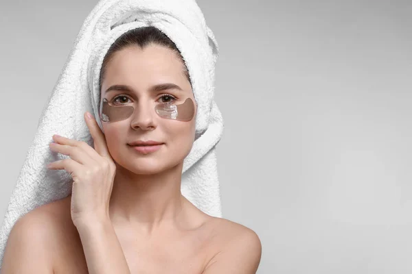 Woman with under-eye patches on light background