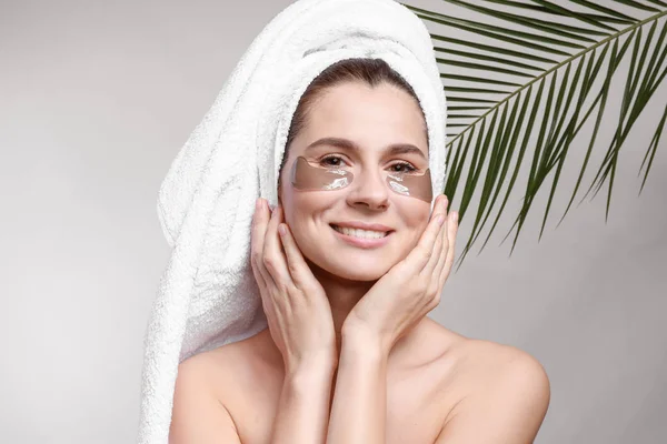 Woman with under-eye patches on light background