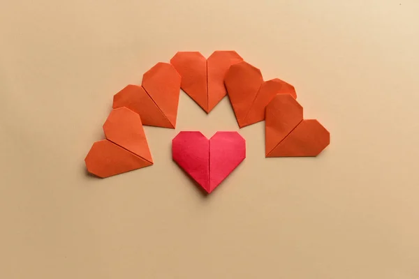 Corazón de papel que difiere en color de otros sobre fondo beige. Concepto de singularidad — Foto de Stock