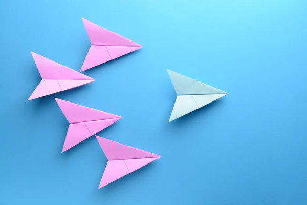 Blue paper airplane among pink ones on color background. Concept of uniqueness — Stock Photo, Image