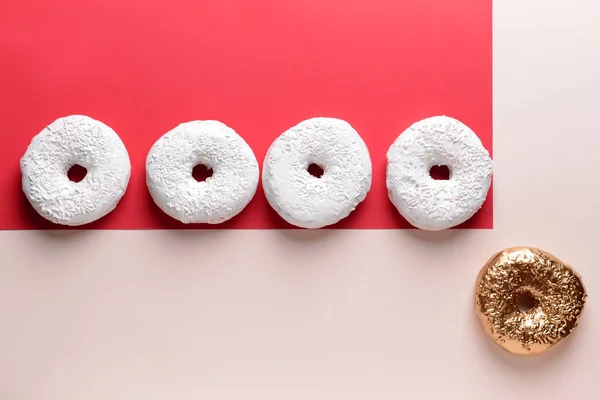 Goldener Donut zwischen weißen auf farbigem Hintergrund. Konzept der Einzigartigkeit — Stockfoto