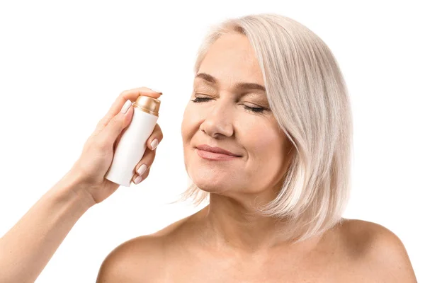 Kvinnlig hand tillämpa serum på mogna kvinnans ansikte mot vit bakgrund — Stockfoto