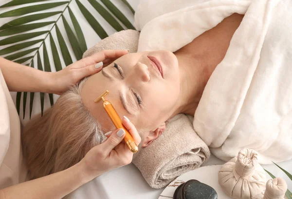 Mature woman receiving face massage in beauty salon — Stock Photo, Image