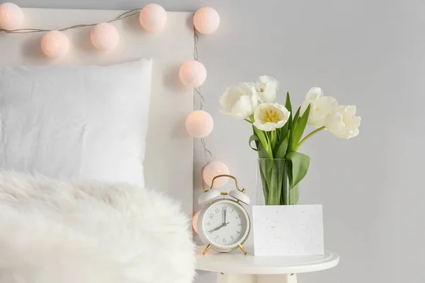 Букет красивых цветов и часов на столе в спальне — стоковое фото