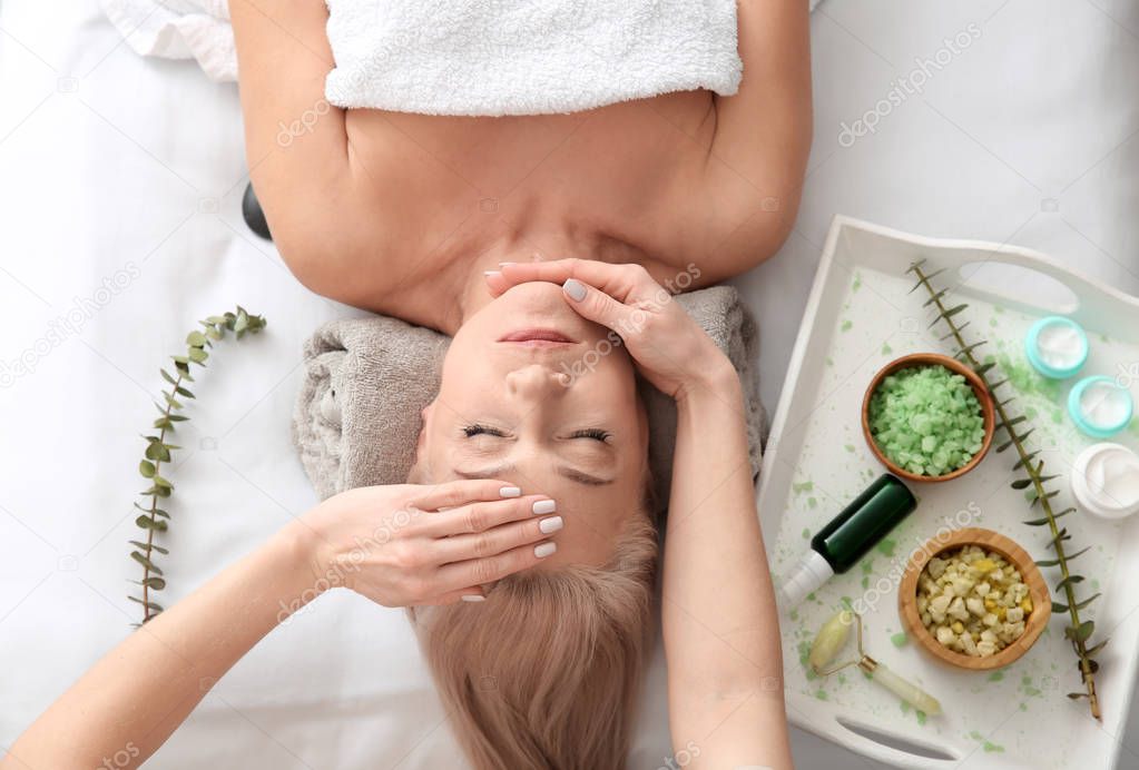 Mature woman receiving face massage in beauty salon