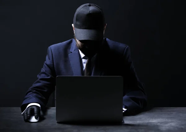 专业黑客与笔记本电脑坐在桌子上的黑暗背景 — 图库照片