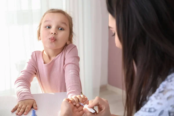 Cute daughter with mother making manicure at home — Stock Photo, Image